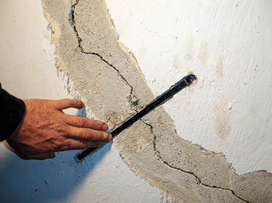 A wall with a large crack is being inspected by a professional in Stockton, CA